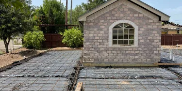 Rebar grid laid out for a new residential concrete driveway pour beside an RGV brick home