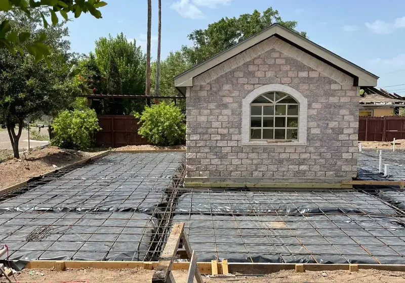 Rebar grid laid out for a new residential concrete driveway pour beside an RGV brick home