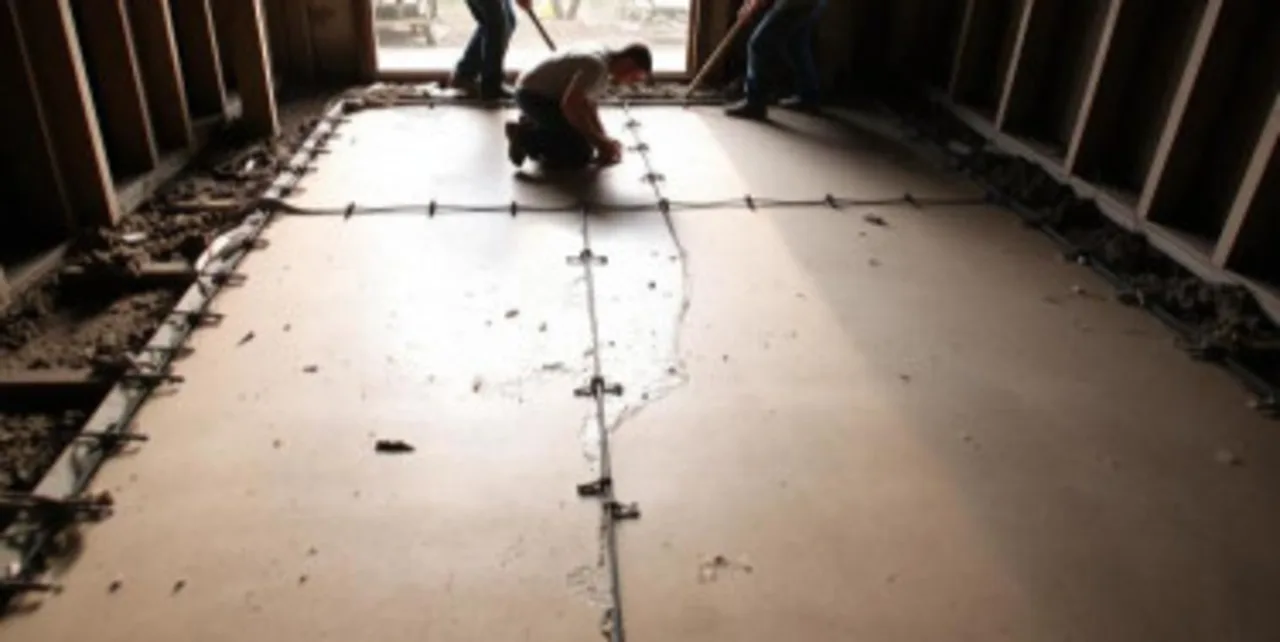 Worker finishing a fresh poured concrete slab over a former wood subfloor with rebar grid in an RGV home